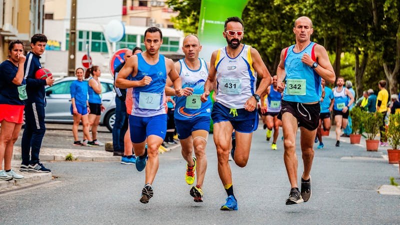 Grupa sportista trči na atletskoj stazi tokom treninga