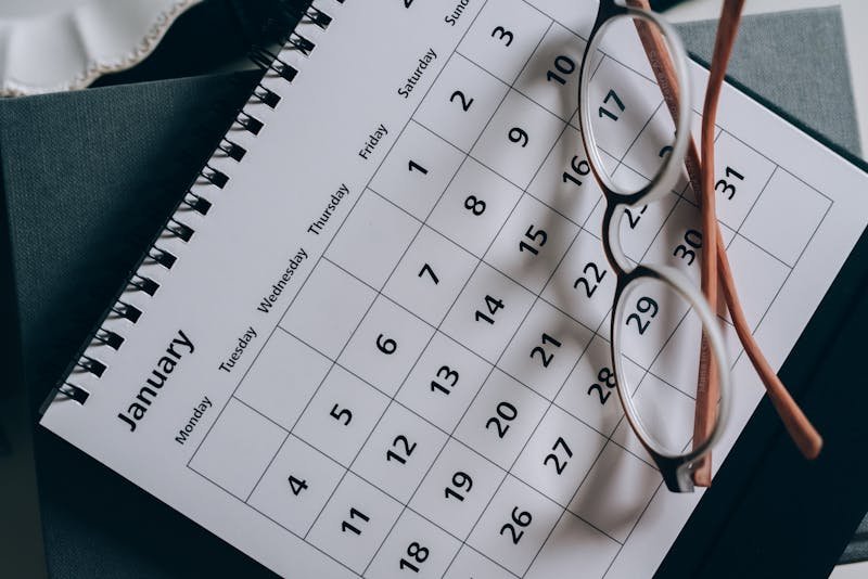 Naočare položene na kalendar, prikaz planiranja vremena i organizacije
