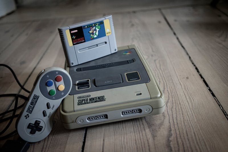 Retro džojstik i stara konzola na drvenom stolu sa kasetom